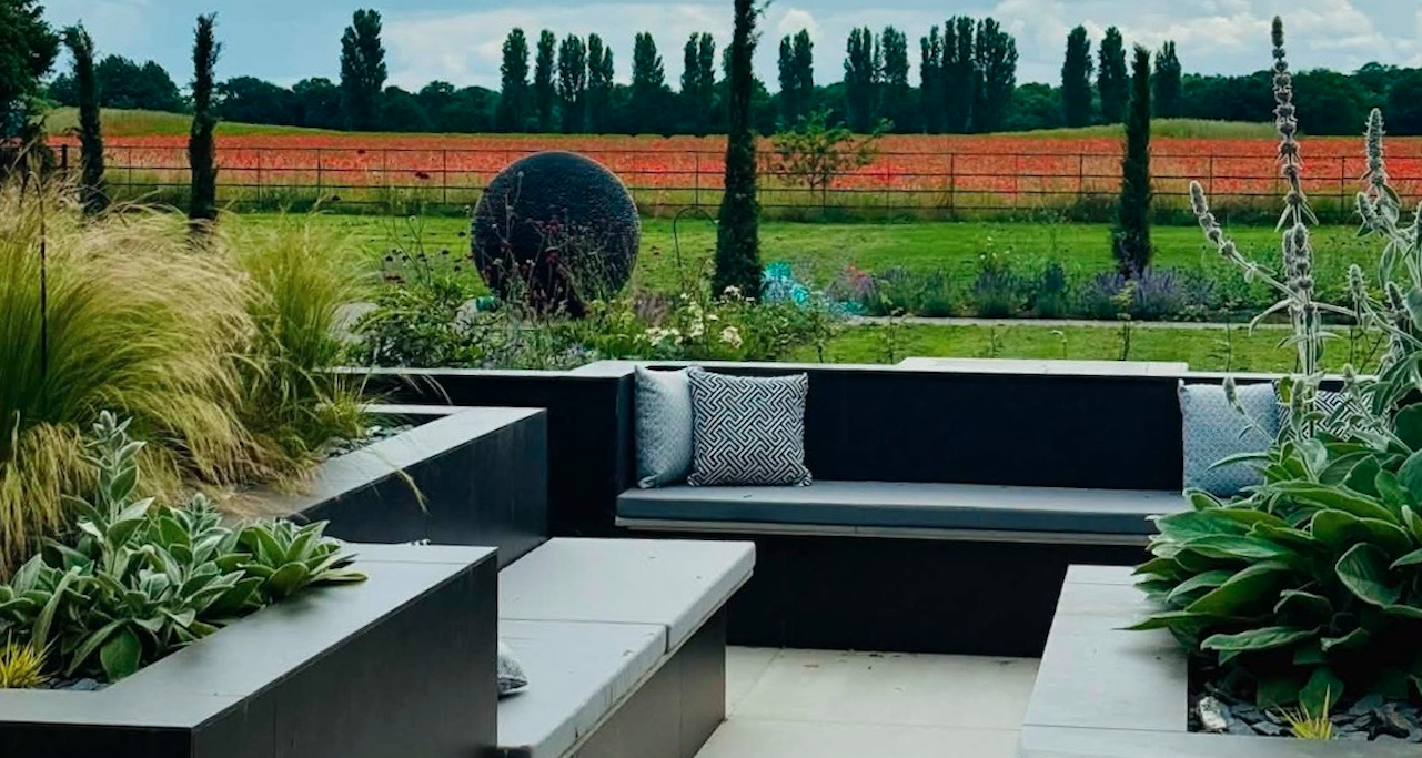 Contemporary garden with built-in seating, dark paving and garden sculpture — garden design by Will Draper, Norfolk